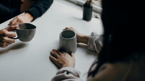 Two people sit together and discuss over coffee. Courtesy of Pixaby.