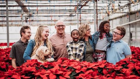 The Vos Family in a greenhouse among poinsettias. 