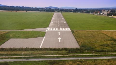 an airport runway on a sunny day with some hills in the distance
