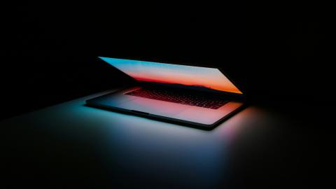 A laptop halfway open with a dark background. 