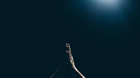 Image of hands at prayer held up against a black background. Courtesy of Unsplash.