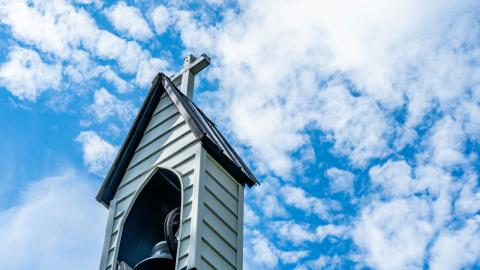 A church steeple stands proudly in a blue sky. Courtesy of chris robert on Unsplash.