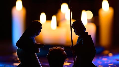 An image of a creche standing before a set of candles. Courtesy drehkopp on Pixaby.