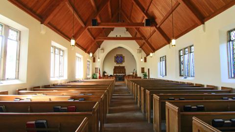 Interior of a church from the back, with the pews in front and the altar in the far front of the image.