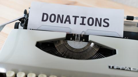 A piece of paper with the word "donations" sticks out of a typewriter.