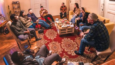 Resonate missionary Jeff Bouman sits in a circle with young adults in a warmly-lit living room