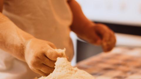 a child touches bread dough on a red and white table cloth