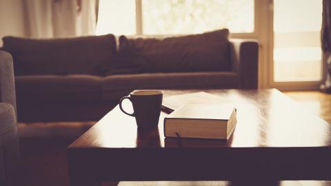 A mug and large book sit on a coffee table in a living room