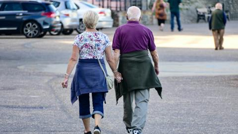 A couple hold hands and walk together along a road