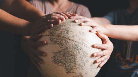 Hands praying over a globe