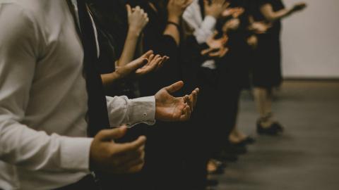 Individuals stand together in a circle praying together.