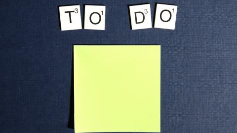 Scrabble letters writing out "to do" are present above a sticky note on a black background