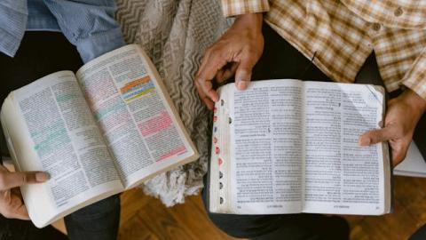 Two people sit together with their bibles open. Courtesy of Timo Miroschenko on Pexels.