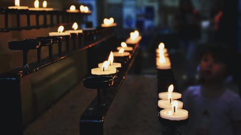Lit candles burn in a church