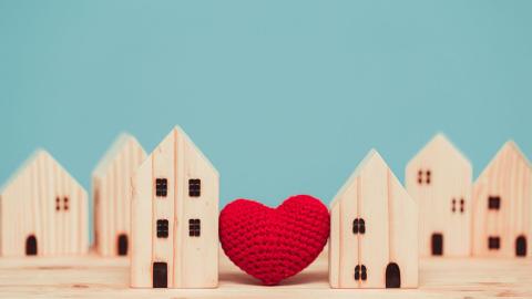 A crocheted heart among wooden cut outs of houses