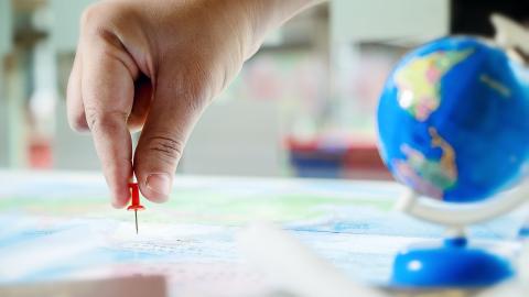 A hand placing a pin in a map