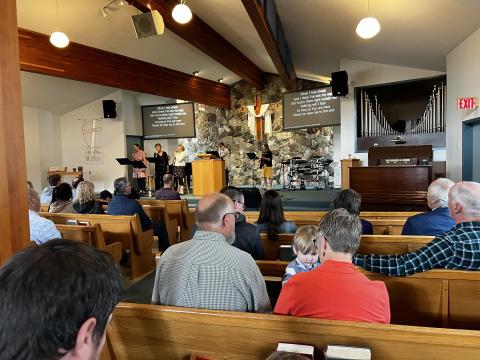 People sitting in church pews singing "Thy Word is a Lamp Unto My Feet."