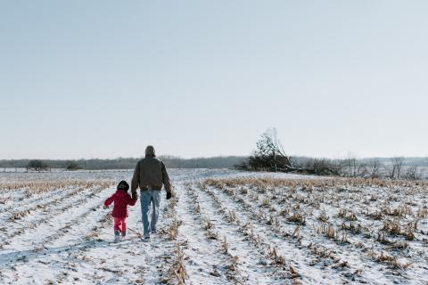 An adult and a child walking through a snowy field Image by Kelly Sikkema